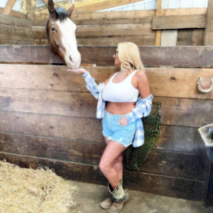 Blonde amateur Maddie Cross unveils her hefty tits while getting naked in a horse stall