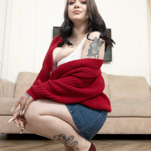Tattooed solo female Kira Clark unleashes her gigantic tits in high heeled shoes on a couch