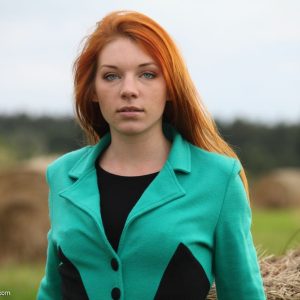 Charming redhead Amber's first nude outdoor modeling in a sunlit field